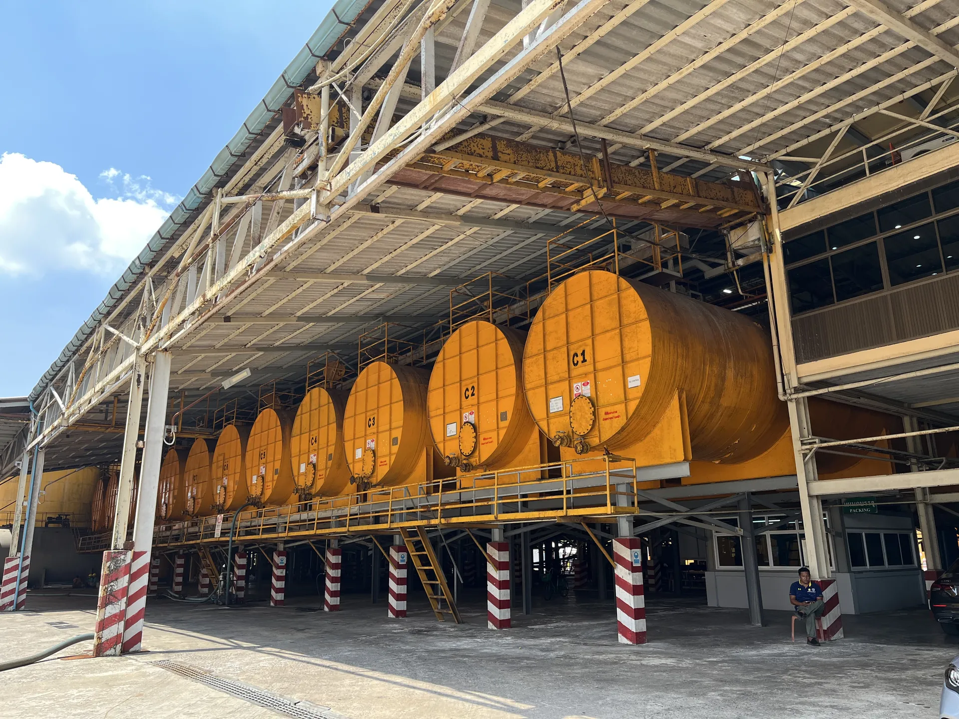 Row of elevated amber concentrate tanks on striped support columns