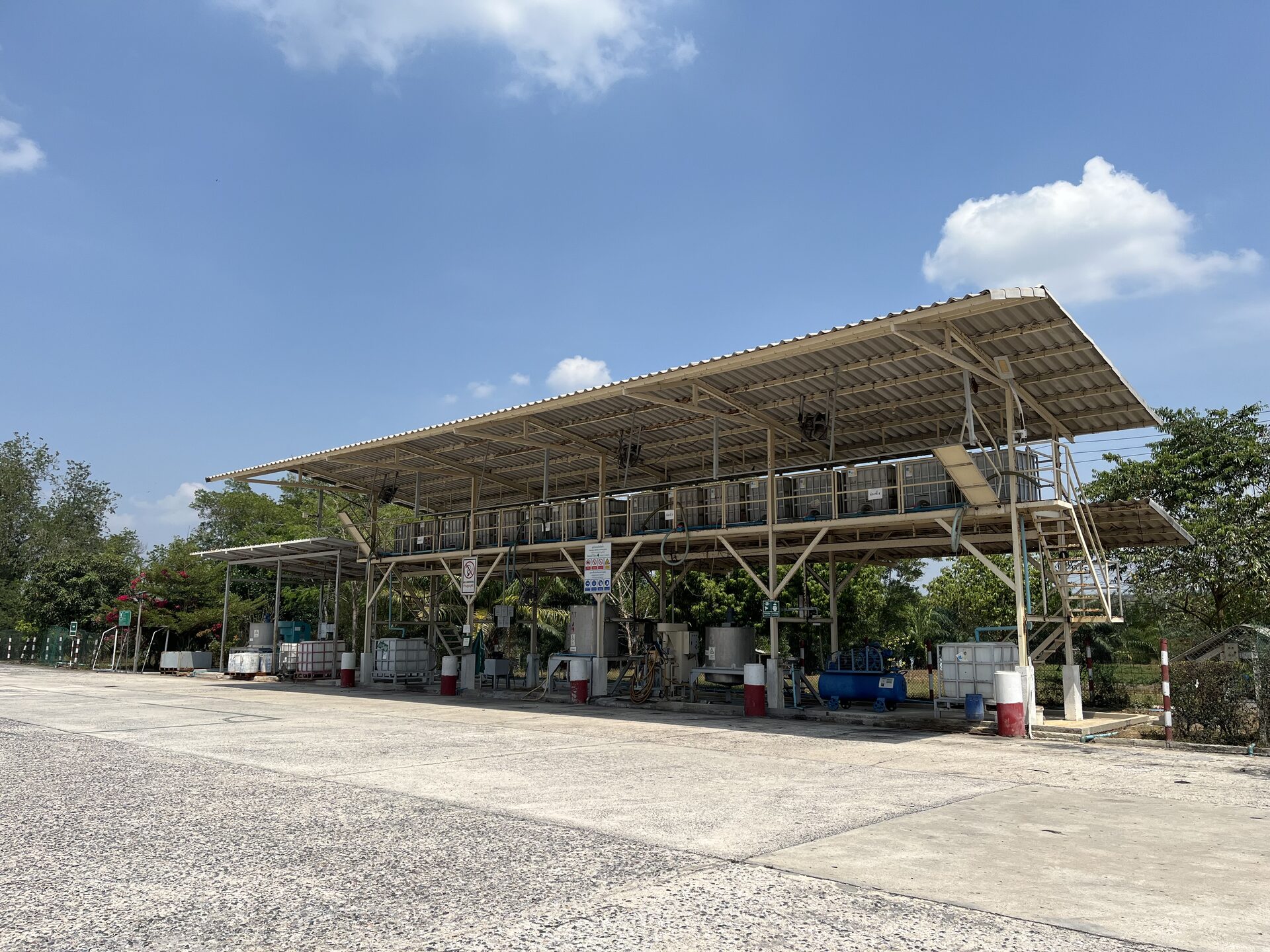 Open-air field latex intake station under a long canopy