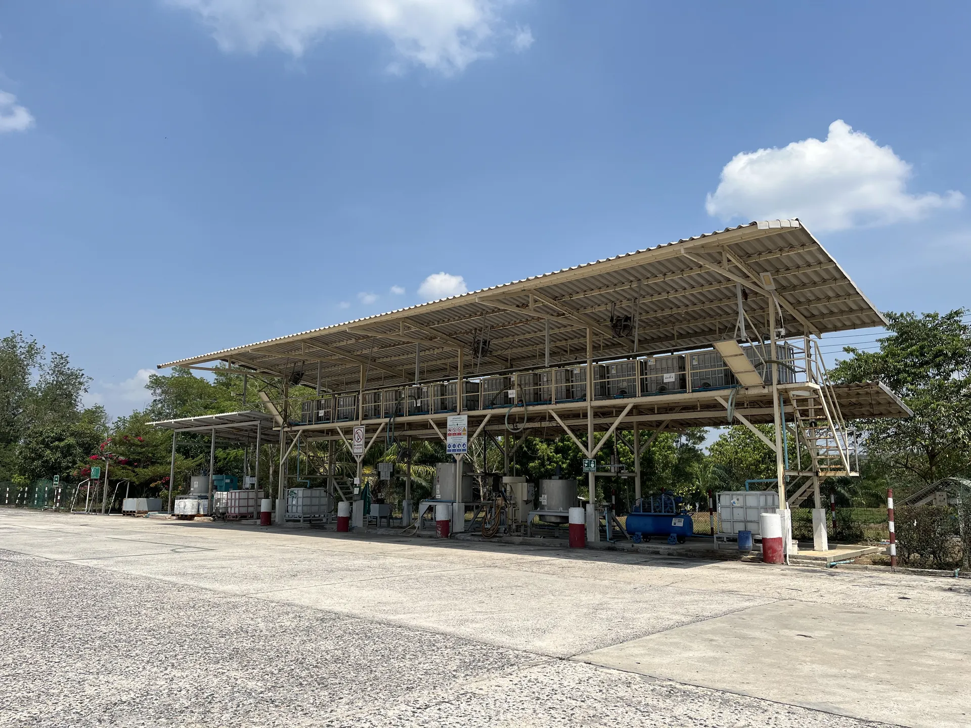 Open-air field latex intake station under a long canopy