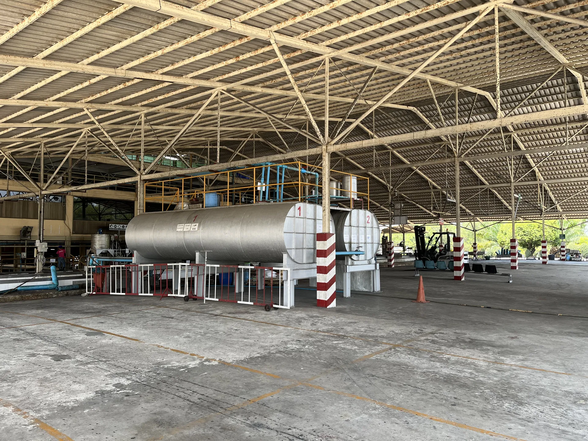 Large stainless steel bulk latex blending tanks inside a covered hall