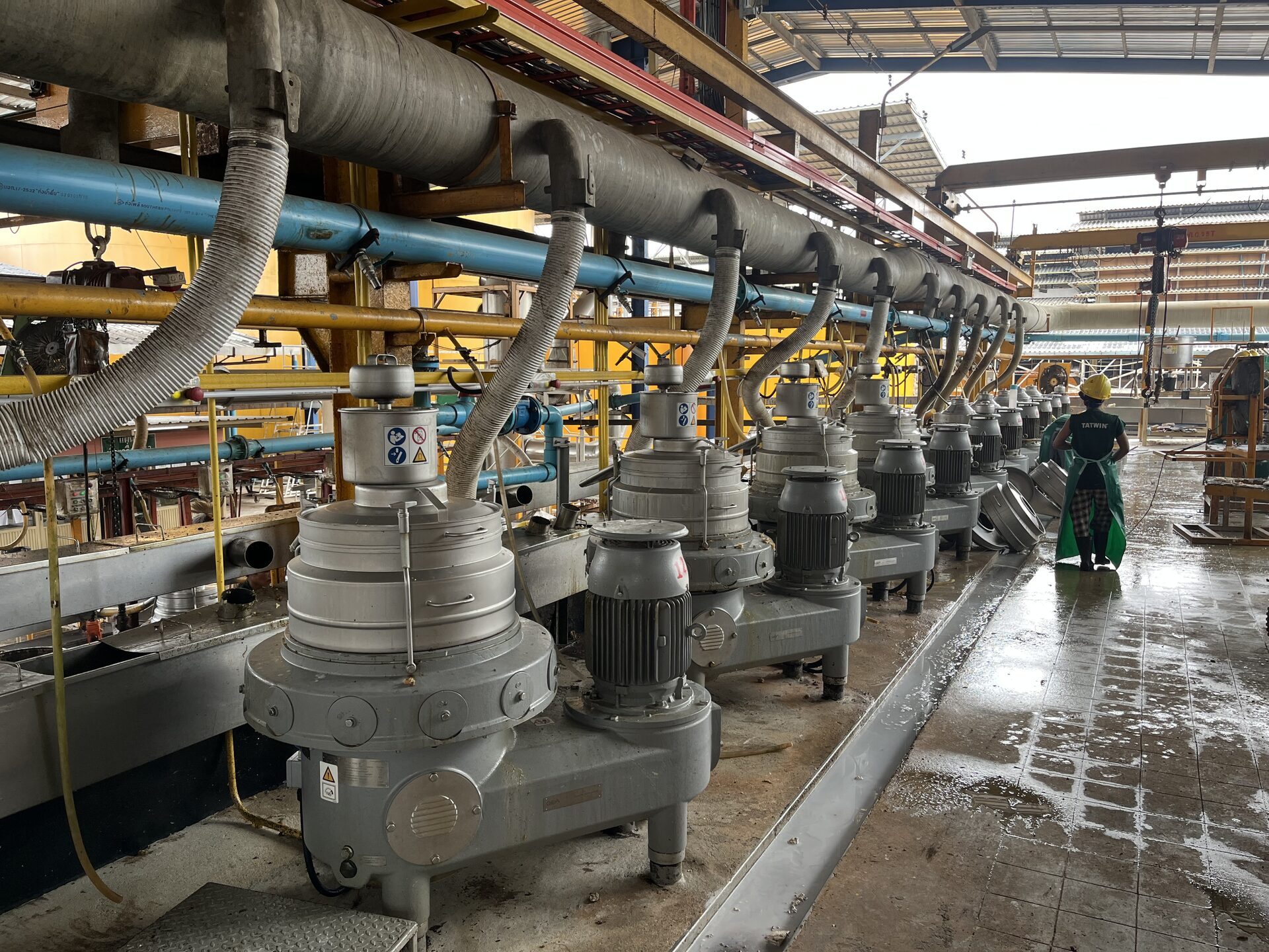 Long row of latex centrifuge separators with a worker walking the aisle