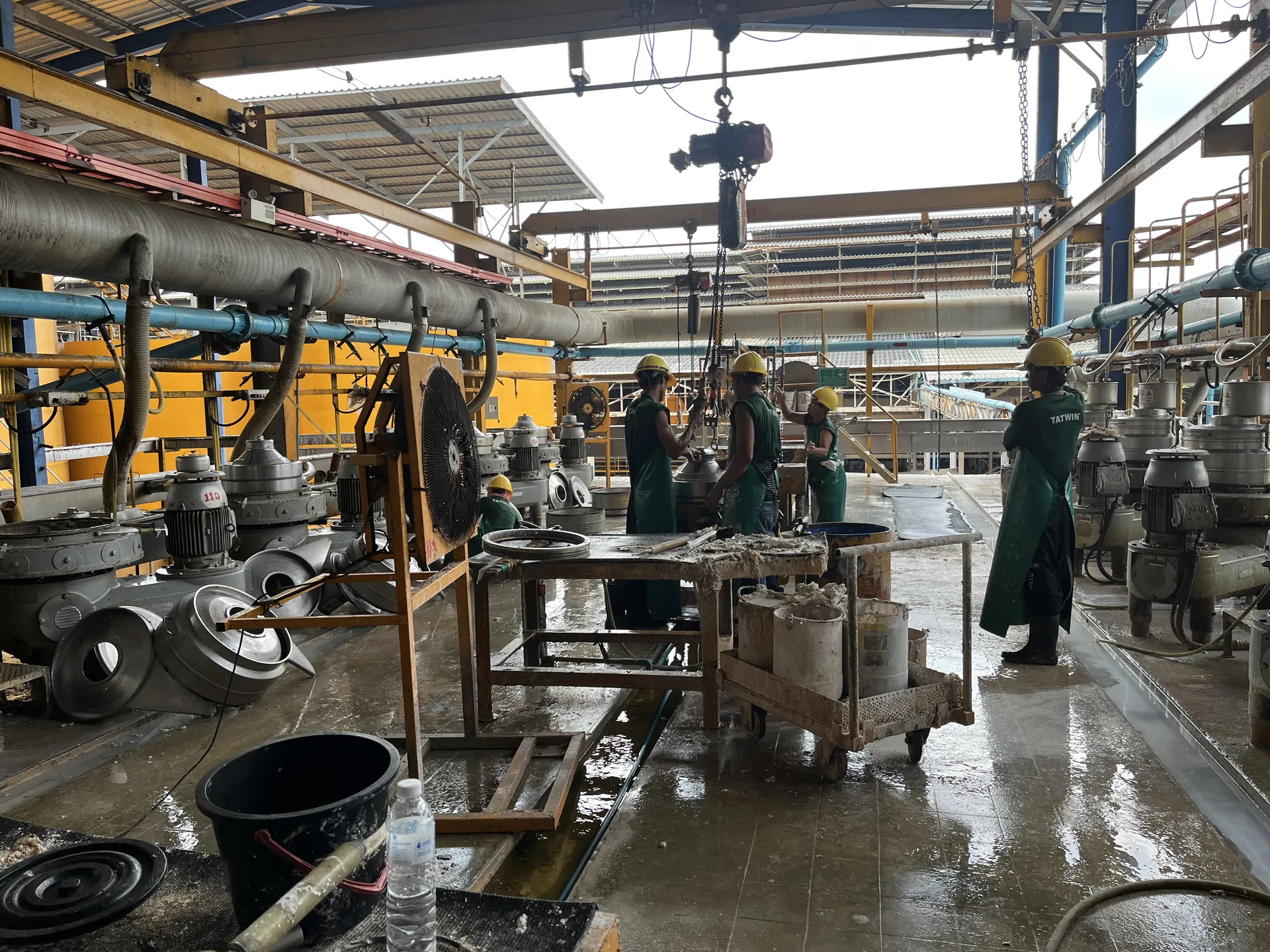 Tat Win workers servicing centrifuge bowls at a maintenance bench