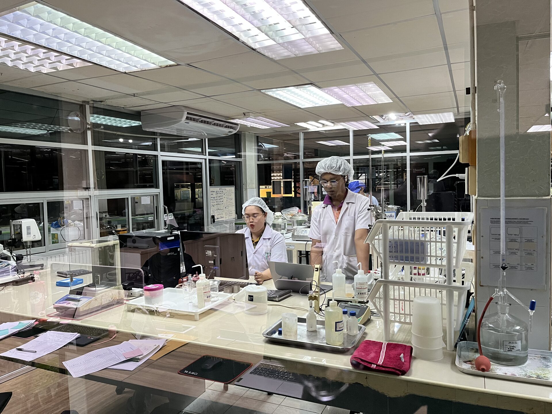 Lab technicians running latex quality tests with glassware