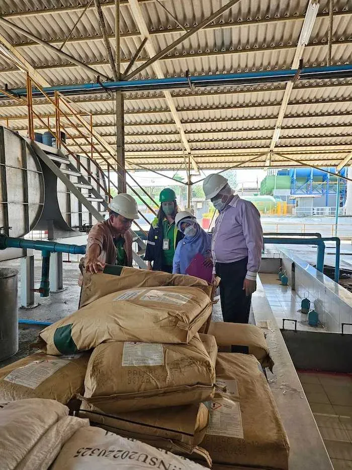 Tat Win staff in hard hats inspecting material at the plant